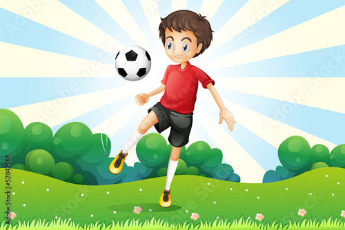 A boy practicing soccer at the hilltop