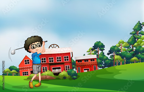 A boy playing golf near the barn