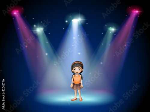 A smiling girl standing on the stage with spotlights