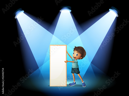 A boy holding an empty board with spotlights