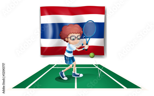 A boy playing tennis in front of the Thailand flag