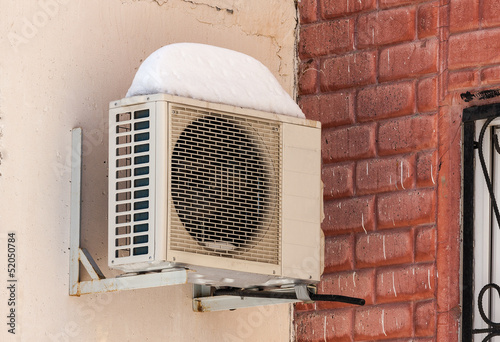 Air conditioning heat pump mounted on brick wall.