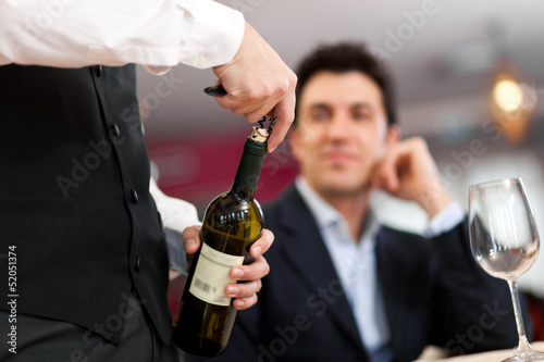 Waiter serving wine to a customer