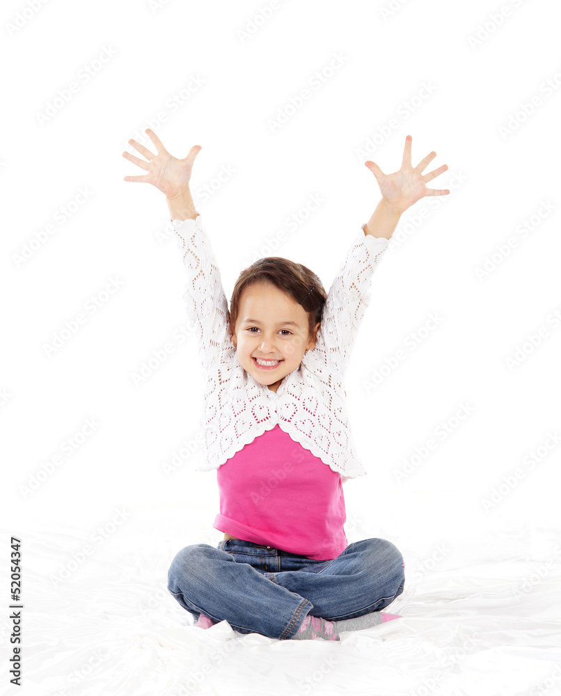 A happy little brunette girl in jeans isolated on white