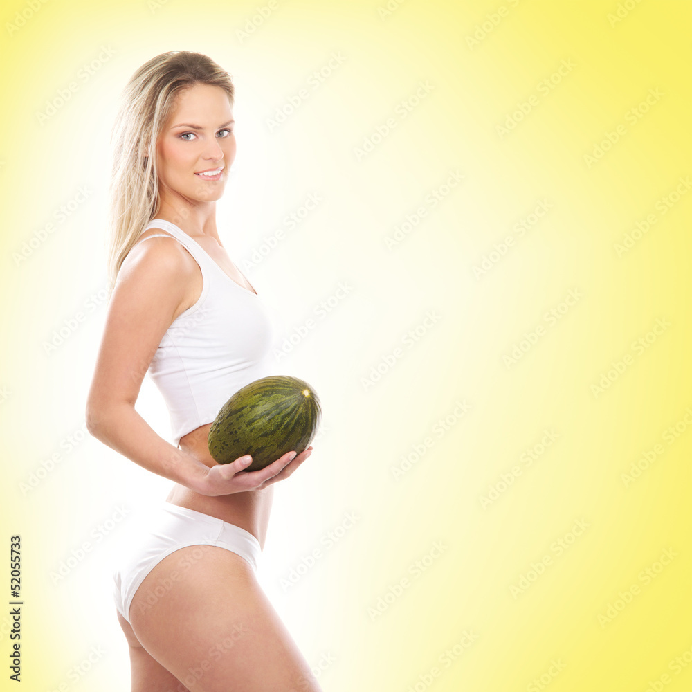 A young and sexy girl holding a melon on a yellow background A young and sexy girl holding a melon on a yellow background