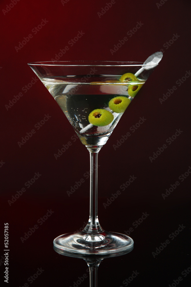 Martini glass with olives on dark red background