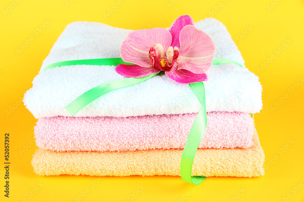 Towels tied with ribbon on yellow background Towels tied with ribbon on yellow background