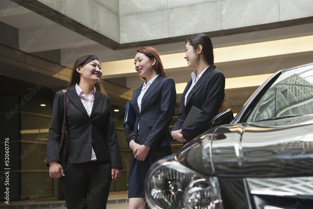 Three young businesswomen meeting and talking in parking garage