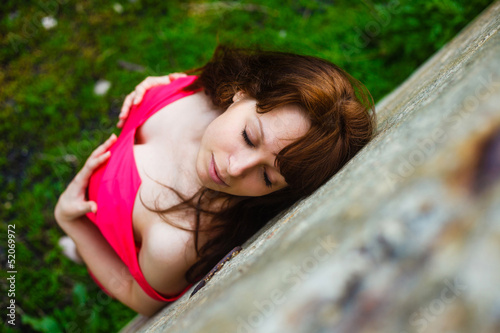 brunette girl closed her eyes in red dress on a green backgrou