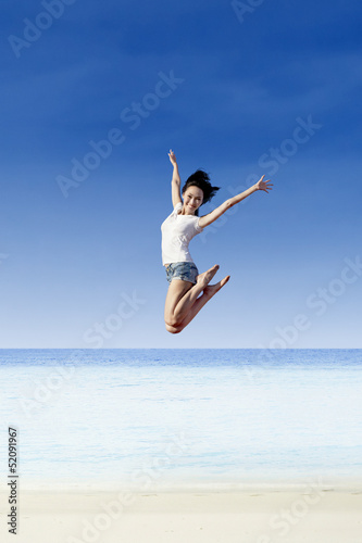 Asian girl jump at white sand beach