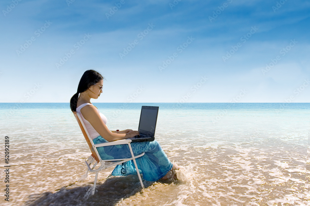 Attractive woman typing on laptop at beach