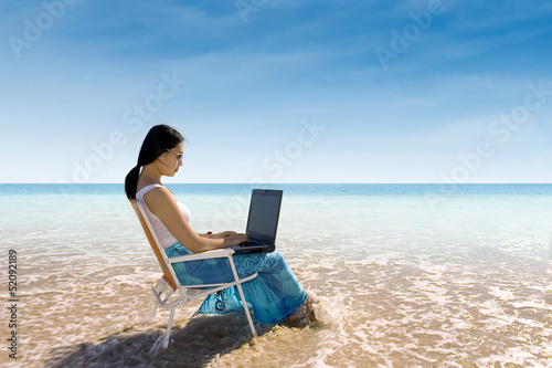 Attractive woman typing on laptop at beach © Creativa Images