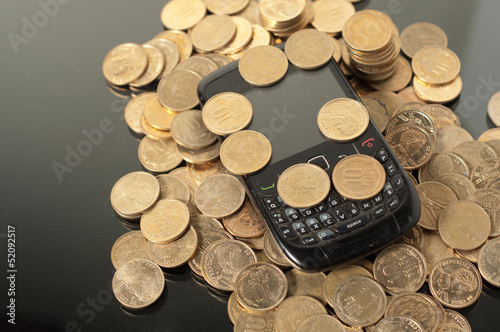 monete e cellulare su sfondo nero