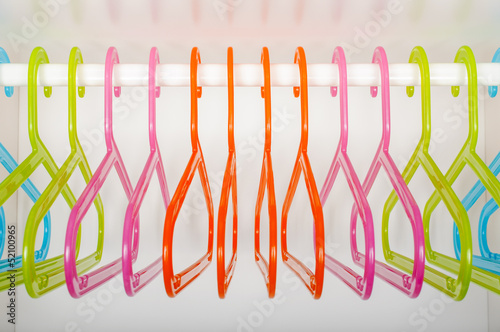 Colored hangers on a rod in a wardrobe