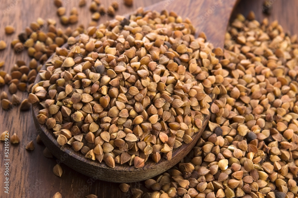Buckwheat seeds on wooden spoon in closeup Buckwheat seeds on wooden spoon in closeup