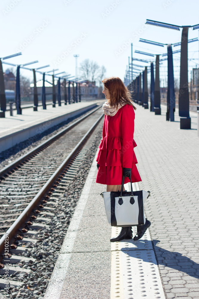 young woman in red at a train station