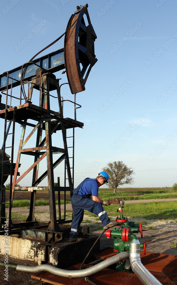 oil worker with pipe wrench and pipeline