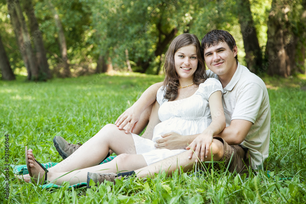 Pregnant wife and her husband on green grass Pregnant wife and her husband on green grass