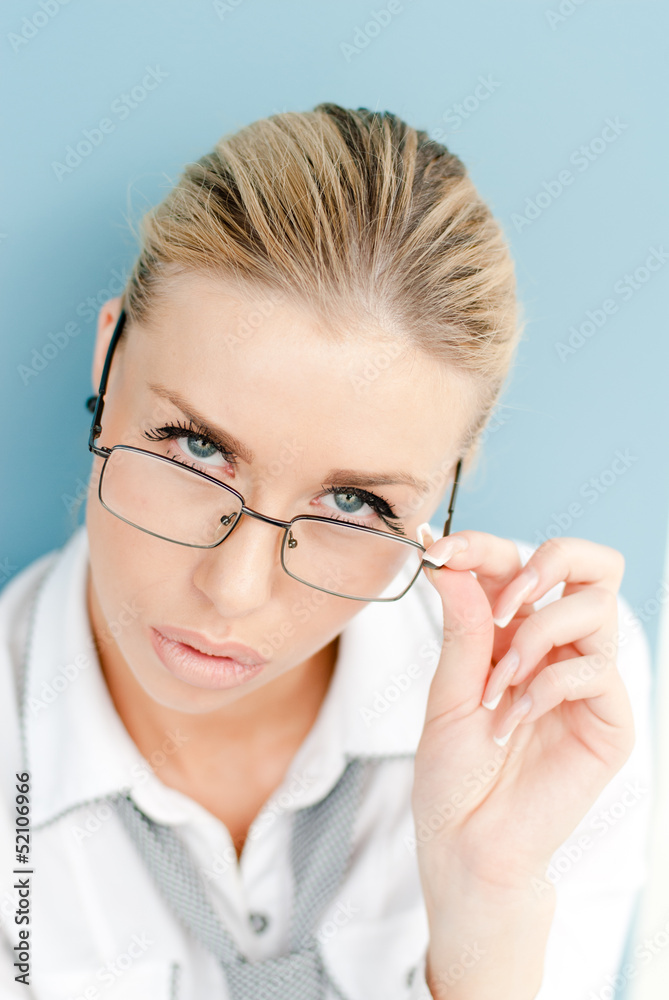 Portrait of a blonde young businesswoman looking over glasses Portrait of a blonde young businesswoman looking over glasses