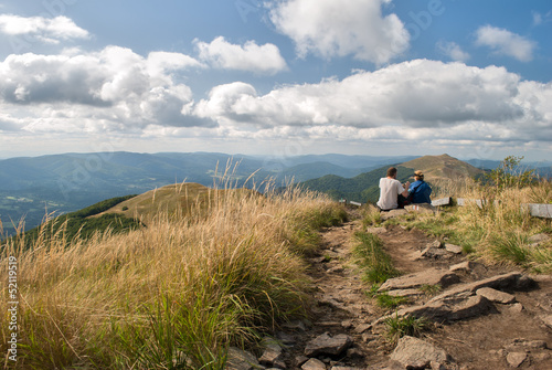 A couple of tourists sit admiring the view in the mountains photo