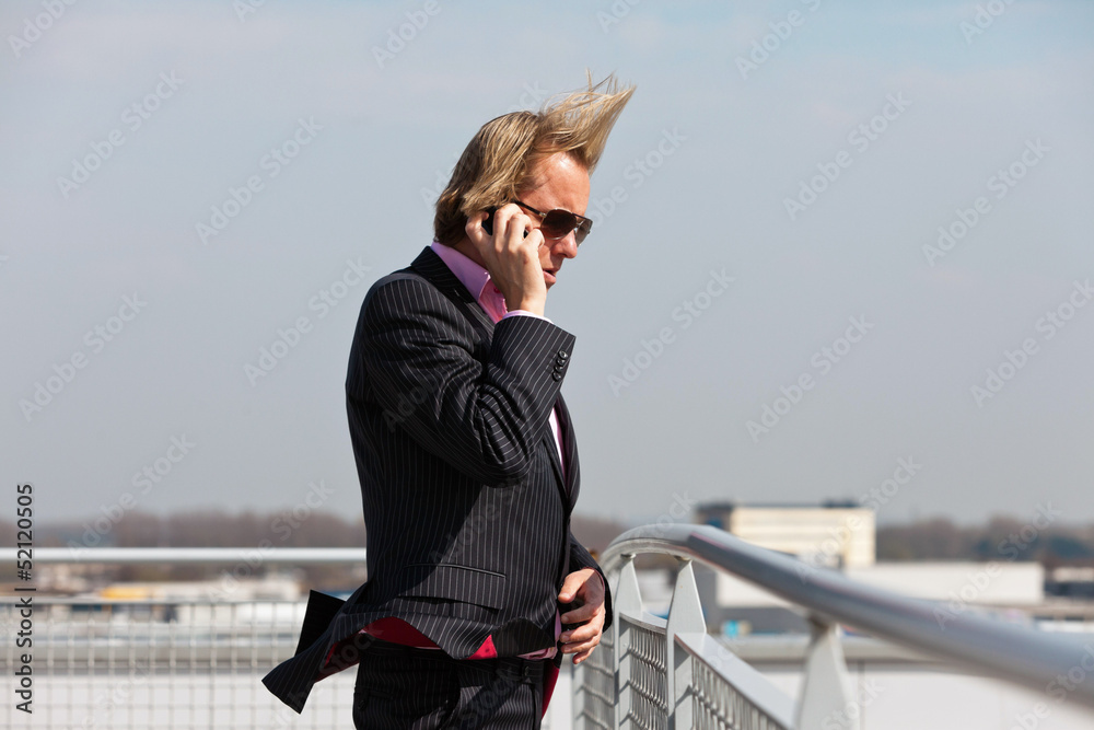 Business man with sunglasses calling with cellphone outdoor on r