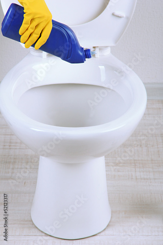 Woman hand with spray bottle cleaning a toilet bowl in a