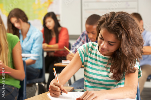 Female Pupil Studying At Desk In Classroom