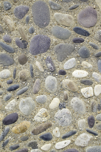 Stones embedded in concrete with loose pebbles