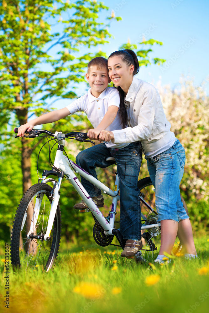 happy mom and son in a green park with a bike happy mom and son in a green park with a bike