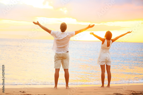 Happy cheering couple enjoying sunset at beach