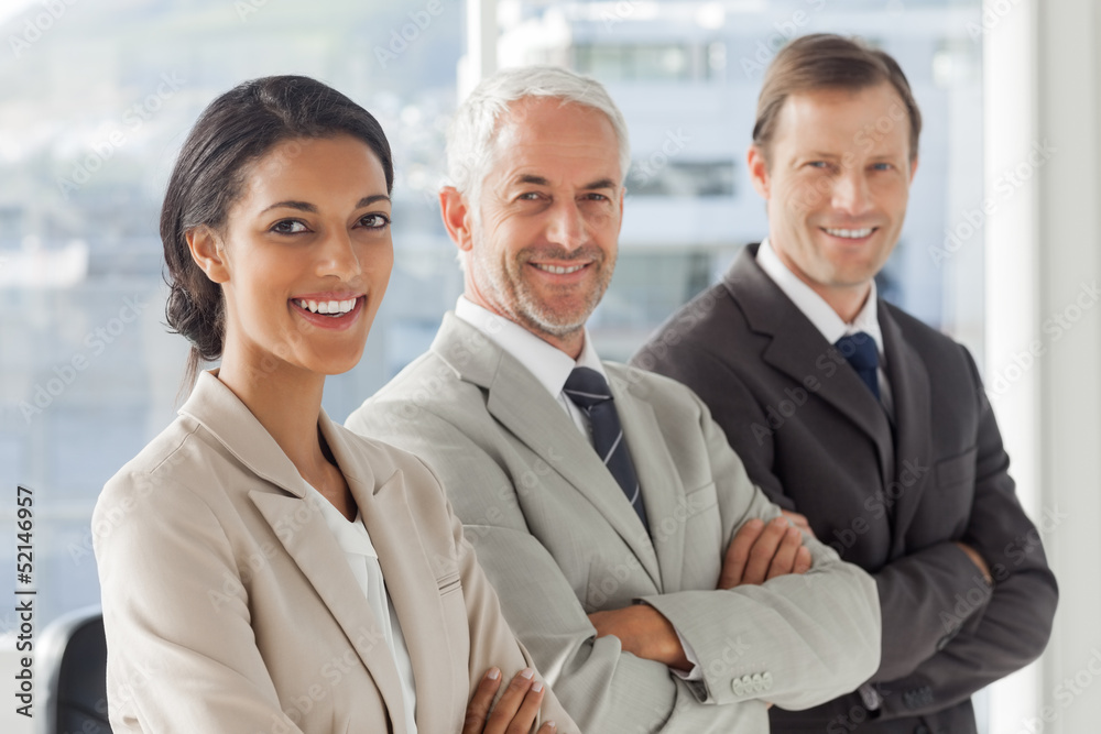 Three business people standing with their arms crossed Three business people standing with their arms crossed
