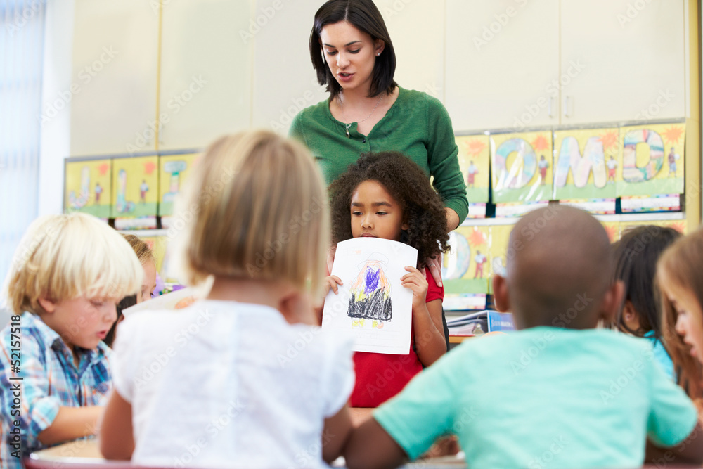 Elementary Pupil Showing Drawing To Classmates In Classroom Elementary Pupil Showing Drawing To Classmates In Classroom