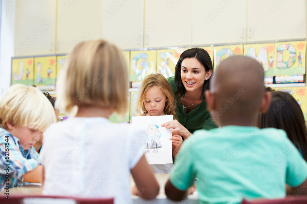 Elementary Pupil Showing Drawing To Classmates In Classroom Elementary Pupil Showing Drawing To Classmates In Classroom