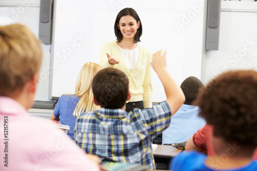 Teacher Standing In Front Of Class Asking Question