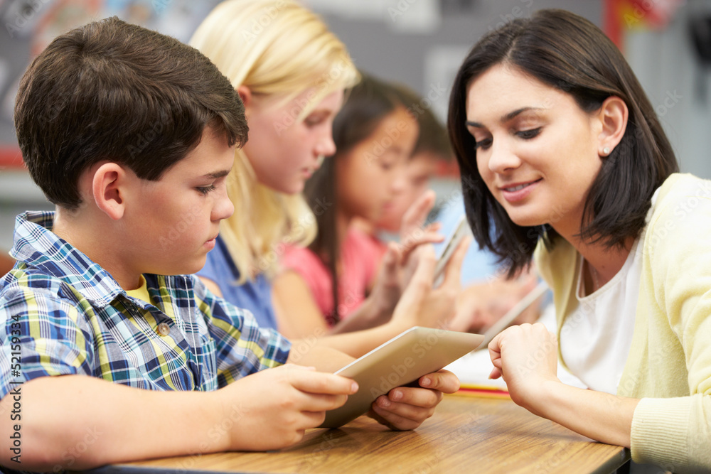 Pupils In Class Using Digital Tablet With Teacher Pupils In Class Using Digital Tablet With Teacher