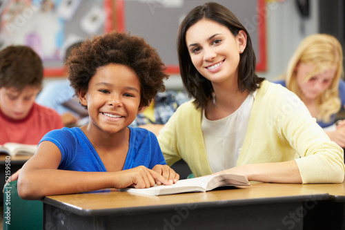 Teacher Reading With Female Pupil In Class