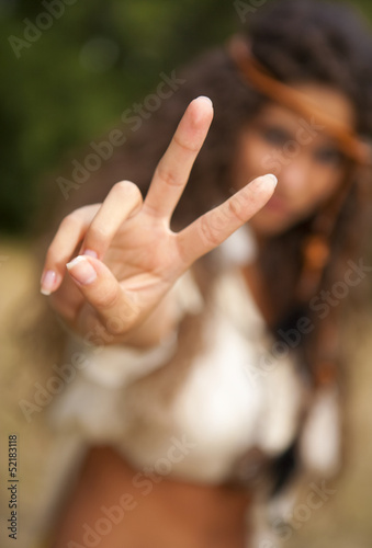 Beautiful hippie girl in the park making the sign of peace
