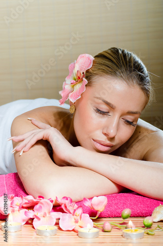 Beautiful woman relaxing during massage with flowers