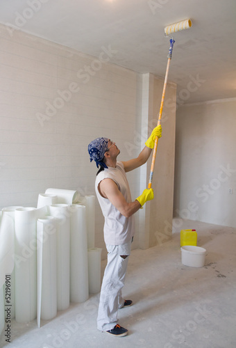 worker painting ceiling with painting roller