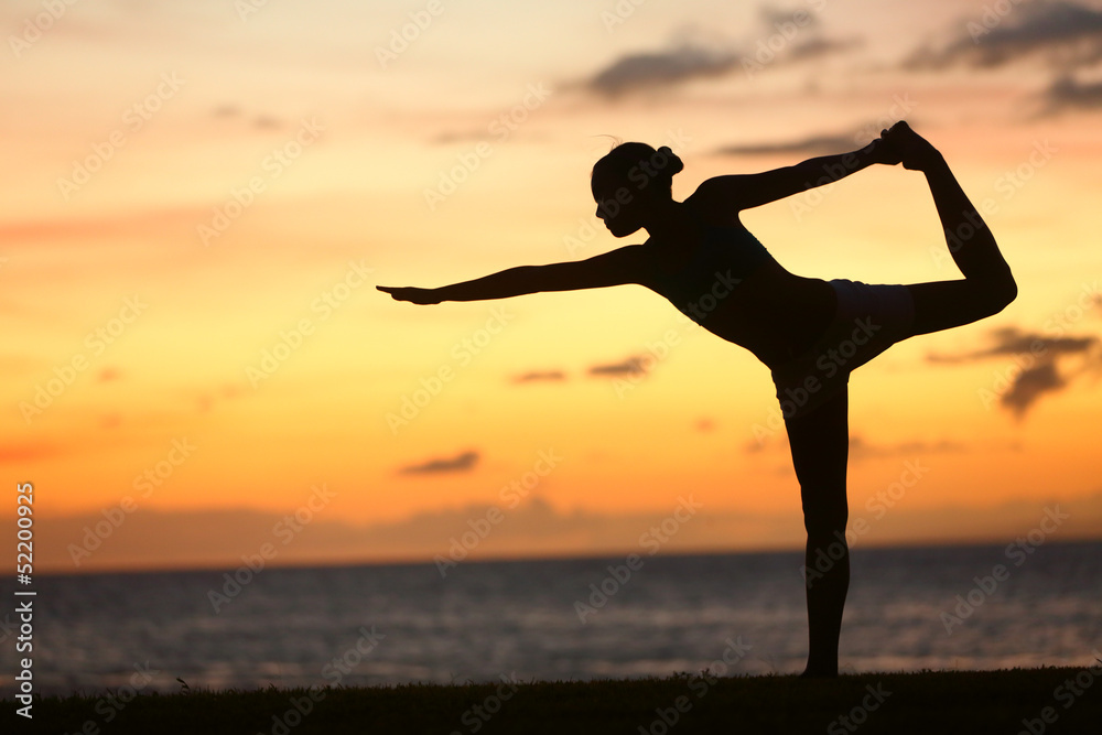 Yoga woman in serene sunset at beach doing pose
