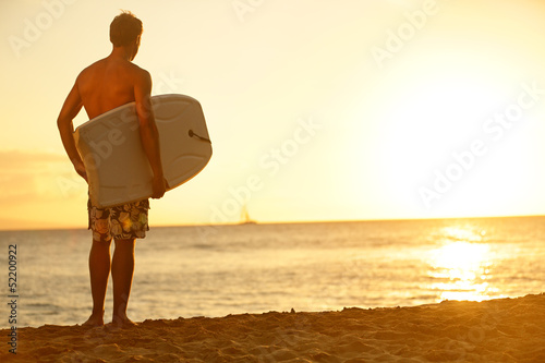Photos Surfer man on beach at sunset holding bodyboard