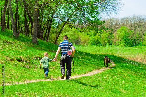 Father with his son and dog for a walk in the woods