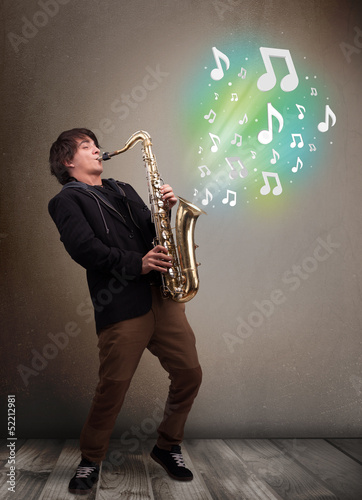 Young musician playing on saxophone while musical notes explodin photo