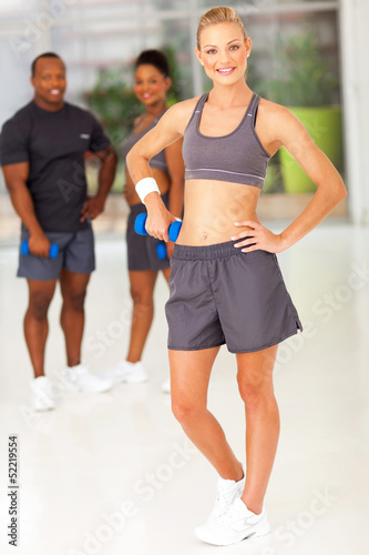 sporty woman posing with friends in gym