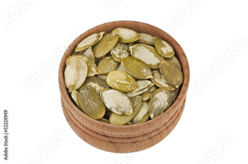 Shelled raw pumpkin seeds in wooden bowl isolated on white