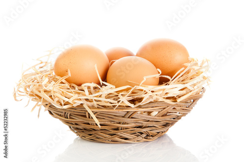 Brown eggs in the basket on white.