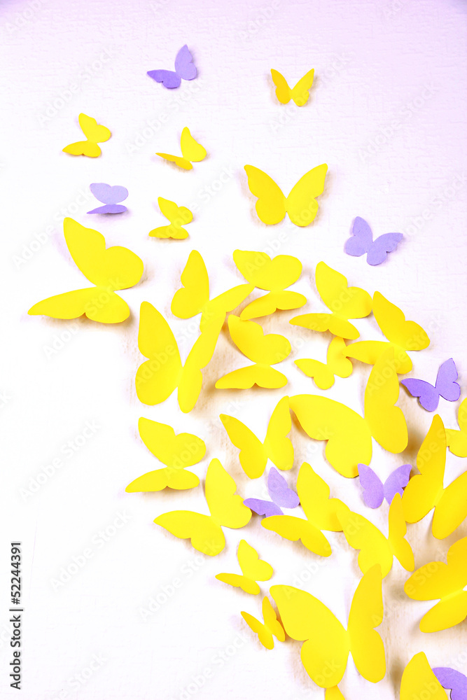 Paper yellow butterfly in form of heart on wall