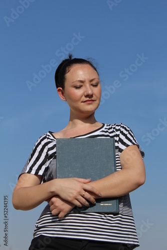 Beautiful brunette young woman outside, holding a book
