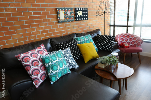 Colorful pillows on a sofa with brick wall in background
