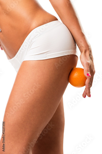 A young girl in underwear with an orange on a white background